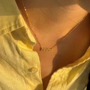 Primer plano de collar dorado con letras MAMA y circonitas llevado por una modelo