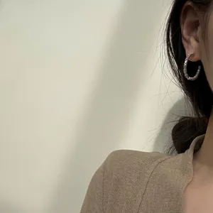 Detail of silver S925 C-shaped earrings with baguette-cut zircon inlay on model