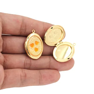 Detailed view of an openable gold-plated oval heart locket pendant being held by hand