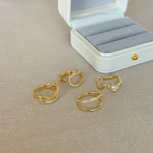 Detailed close-up of a 4-piece set of golden rings with inlaid cubic zirconia and waved lines
