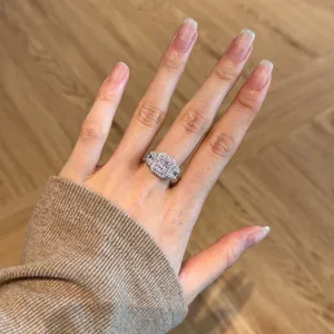 Classic silver ring with large rectangular pink gemstone and halo setting on a finger