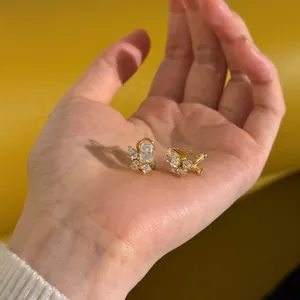 Macro detail of gold earrings with cubic zirconia held in hand for scale and clarity
