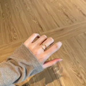 Detail of a thin gold ring with micro-pave white zircon inlay worn on the index finger