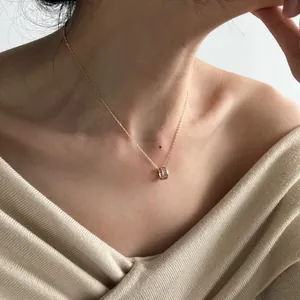 Elegant gold necklace with rectangular purple zircon cylinder pendant on a female model