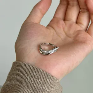 Macro detail of S925 silver wave ring showing layered pavé zircon and smooth metal finish