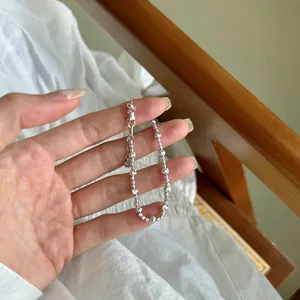 Détail d'un bracelet en argent S925 avec perles polies et dépolies tenu à la main