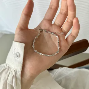 Détail d'un bracelet en perles argentées avec fermoir mousqueton et chaînette