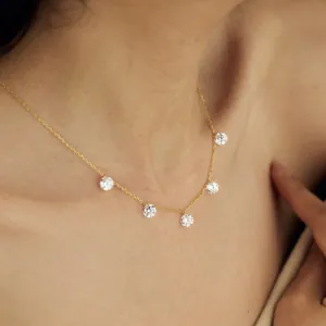 Elegante collana d'oro con cinque zirconi rotondi indossata sul collo di modella