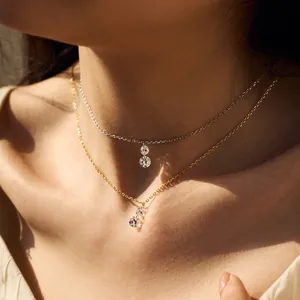 Close-up of layered gold and silver necklaces with round cubic zirconia pendants on model