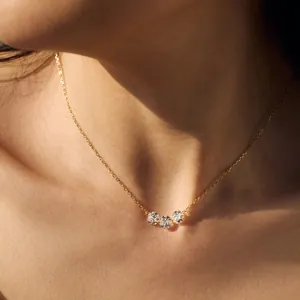 Elegant gold necklace with three sparkling round zircons on a model in natural light