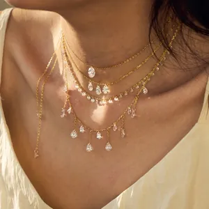 Layered gold necklace featuring clear pear and oval cut zircon charms on delicate chains