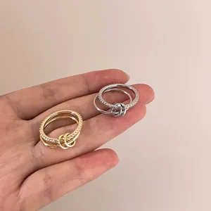 Close-up of elegant entwined silver and gold rings with zircon inlay on hand