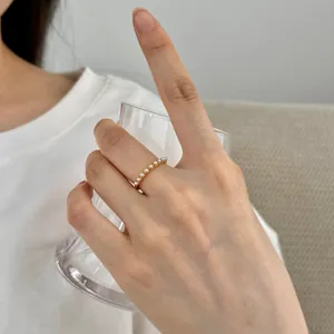 Elegantly minimalist gold ring with a row of small white pearls worn on a female hand
