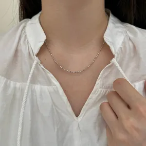 Primer plano de un collar de plata S925 con cuentas minimalistas en el cuello del modelo