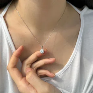 Détail d'un collier pendentif rond en Moissanite étincelante sur le cou d'un modèle