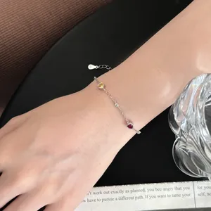 Detailed view of S925 silver bracelet with heart-shaped yellow and pink gems on wrist