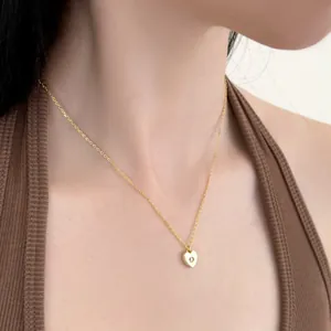 Gros plan d'un collier pendentif cœur doré avec zircon porté au cou d'un mannequin