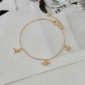 Détail macro du bracelet en argent S925 doré avec breloques abeille et oiseau étincelants