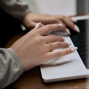 Détail d'une bague dorée ajourée avec zircons portée au doigt d'un mannequin en gros plan