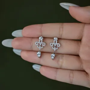 Elegant S925 silver fleur-de-lis earrings with pear-cut cubic zirconia in a hand display