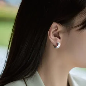 S925 sterling silver hoop earrings with brushed texture worn by a model outdoors
