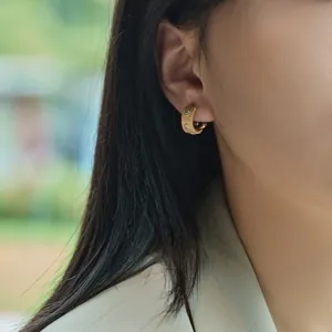 Golden brushed C-shaped hoop earrings with double white zirconia stones on model