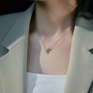 Close-up of a silver bow knot necklace with pavé zircons on a model's collarbone