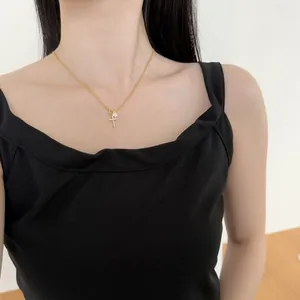Vue détaillée d'un collier croix doré avec pendentif zircon goutte porté par un mannequin