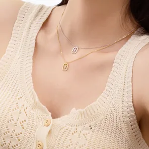 Double-layered gold and silver necklaces with square K letter pendants on a model