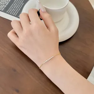 Elegante bracciale dorato con zirconi bianchi incastonati a fila indossato al polso