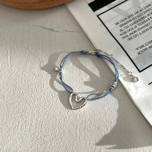 Dettaglio ciondolo cuore argento S925 su bracciale intrecciato blu con zircone