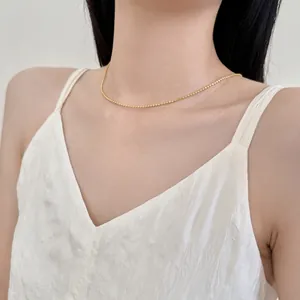 Primo piano di una collana a sfere dorate in argento S925 indossata da una modella