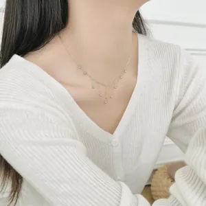 Close-up of S925 sterling silver beaded tassel necklace on model wearing beige knitwear