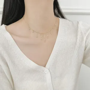 Close-up of a minimalist gold S925 sterling silver beaded tassel necklace on a model