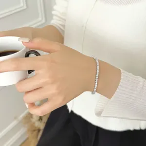 Detail of s925 silver tennis bracelet with round cubic zirconia on model holding coffee