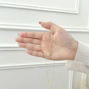 Handheld view of S925 sterling silver gold heart pendant necklace with zircon accents