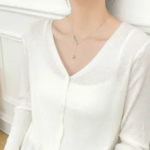Macro shot of silver Y-shaped drop necklace with tiered metal beads on a model's neck