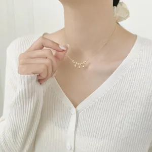 Elegant gold drop necklace with five beads and three droplets on a model's collarbone