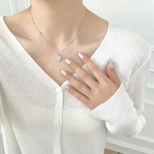 Close-up of S925 sterling silver heart necklace with zircon inlay on model neck