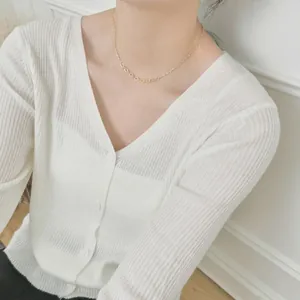 Close-up of gold paperclip link chain necklace worn on a woman's collarbone