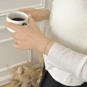 Close-up of S925 silver gold paperclip chain bracelet with a single zircon on woman's wrist