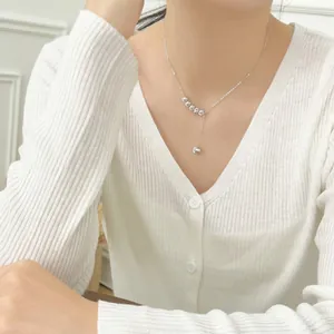 Detail of silver Y-shaped pearl necklace featuring grey cat-eye beads on a model