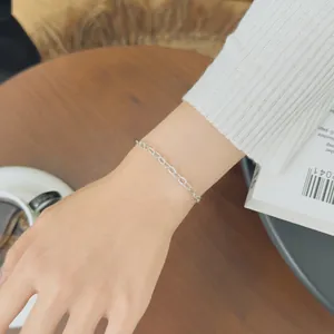 Detail of silver S925 heart paperclip link bracelet on wrist with elegant knit sleeve