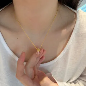 Close-up of golden S925 silver necklace with transparent white crystal lotus pendant