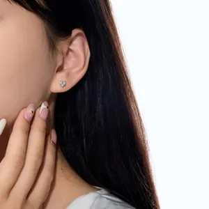 Gros plan d'une boucle d'oreille cœur en argent sterling portée sur l'oreille