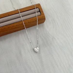 Détail macro d'un pendentif moissanite en forme de cœur sur une chaîne argentée fine