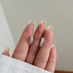 Close-up of S925 sterling silver moissanite stud earrings held in hand for scale