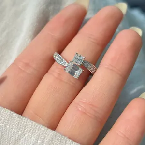 Detailed close-up of bypass ring with emerald and square cut stones on model's finger
