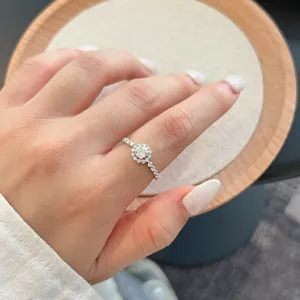 Λεπτομερής προβολή δαχτυλιδιού Moissanite με σχέδιο halo και pavé μπάντα στο δάχτυλο