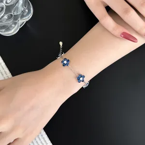Detail of S925 sterling silver bracelet with dark blue zircon flowers on a woman's wrist
